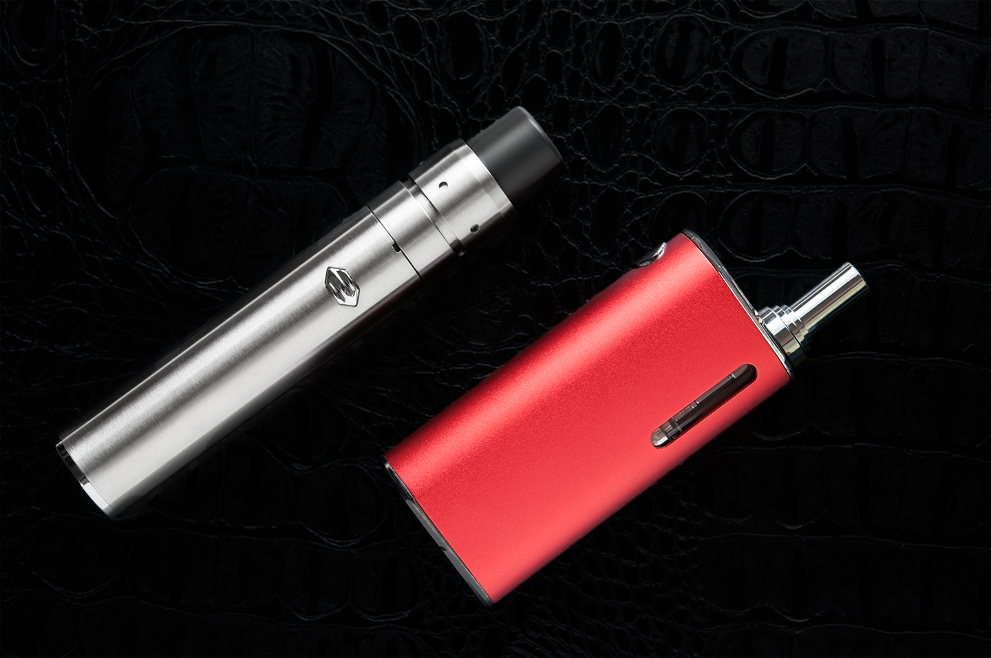 Rechts eine rote, links eine silberne E-Zigarette auf schwarzem Hintergrund