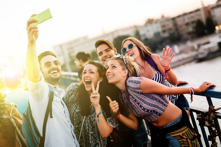 Eine Gruppe von drei Frauen und zwei Männern machen ein Selfie auf einer Brücke