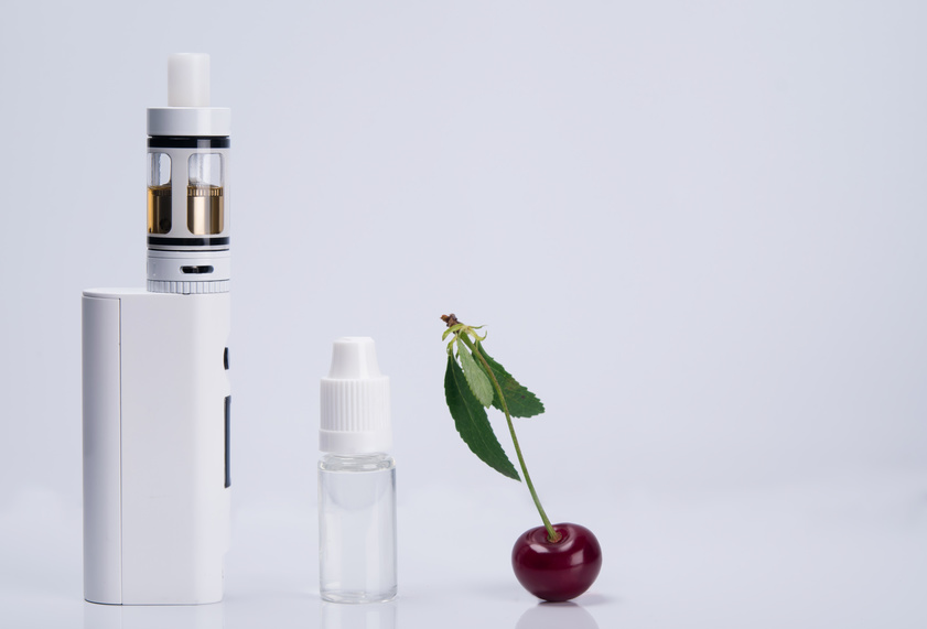 Weiße E-Zigarette mit weißem Liquid-Fläschen und Kirsche (von links nach rechts)