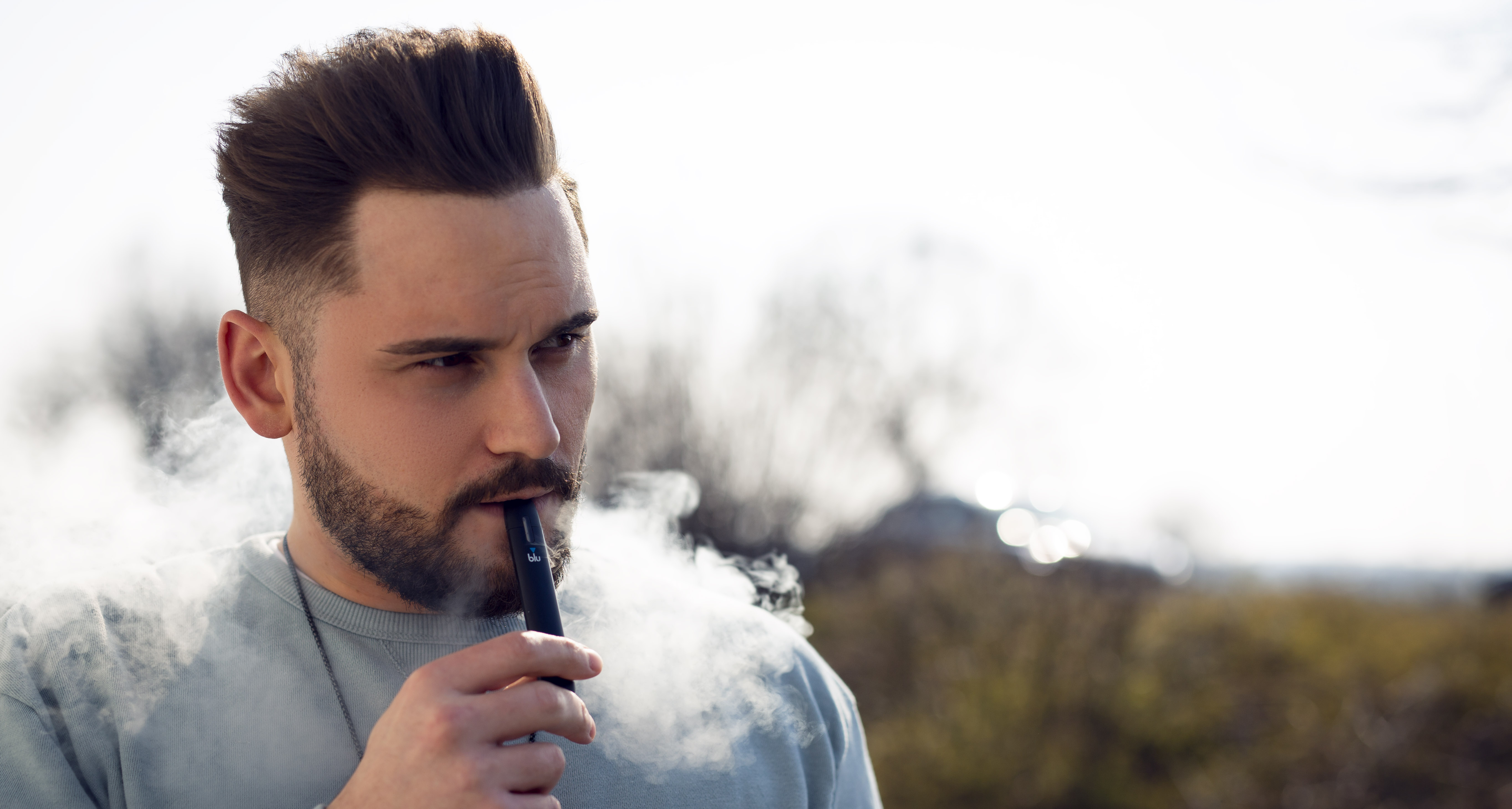 Mann dampft eine blu E-Zigarette