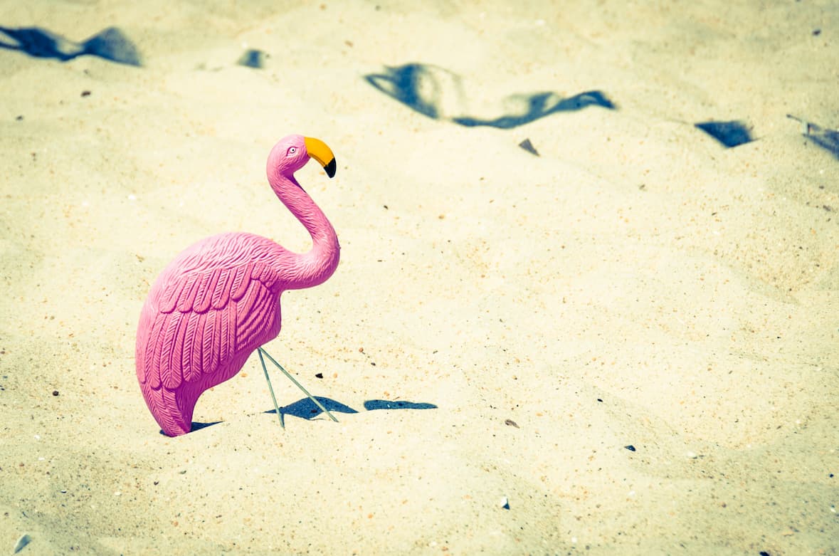 Flamingo aus Plastik im Sand