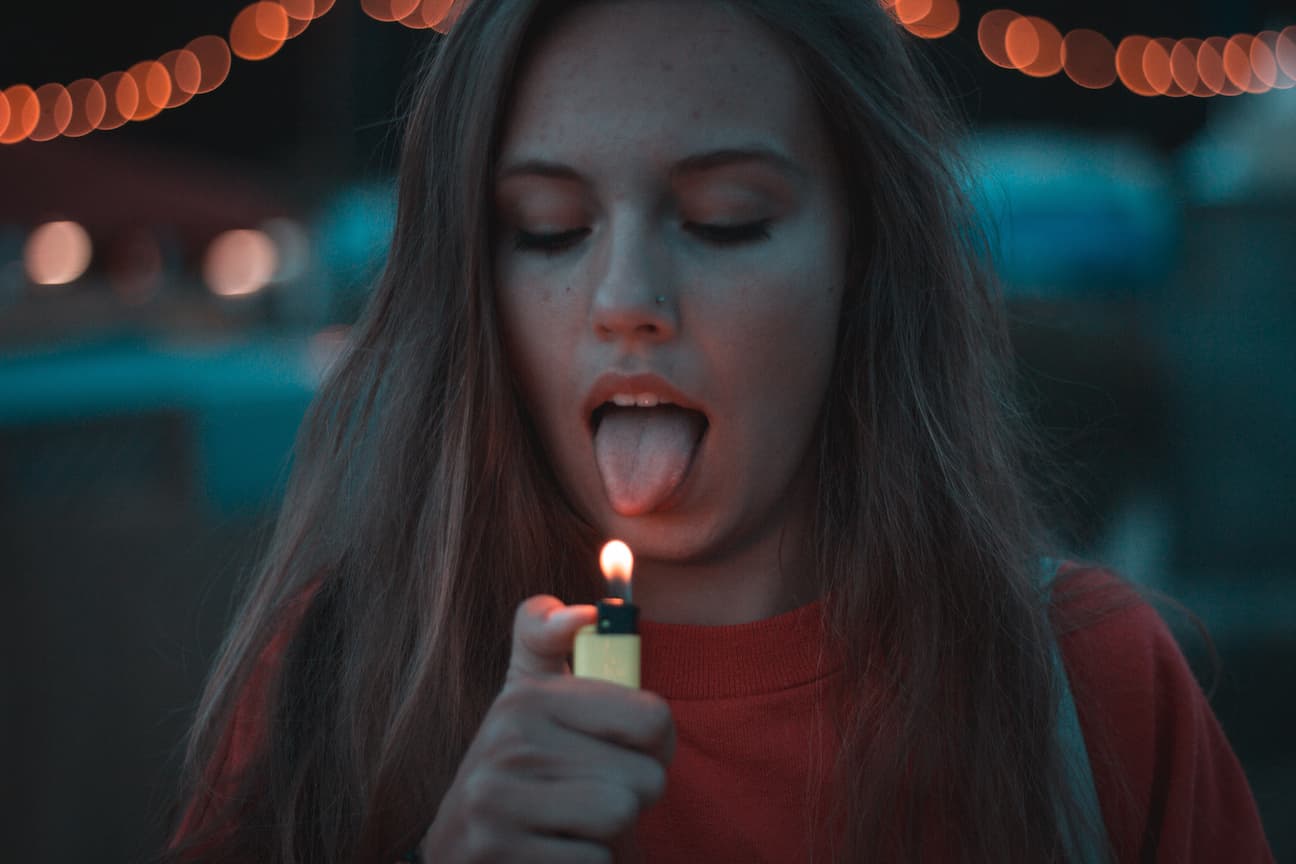 Frau mit brennendem Feuerzeug und herausgestreckter Zunge
