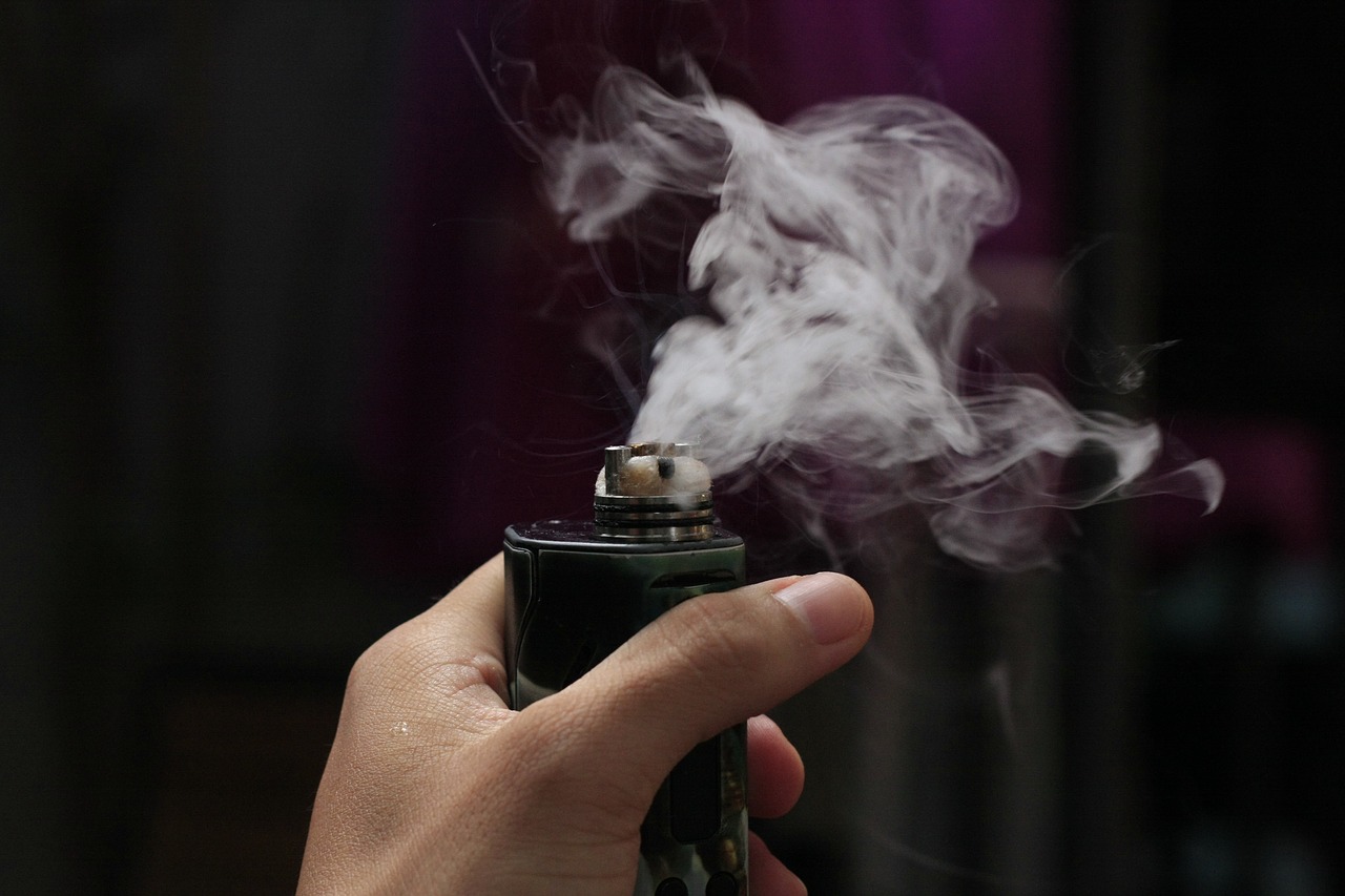 Dampfende E-Zigarette, die von einer Hand gehalten wird