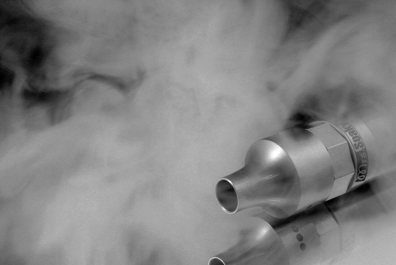 Silberne E-Zigarette liegt in Dampf